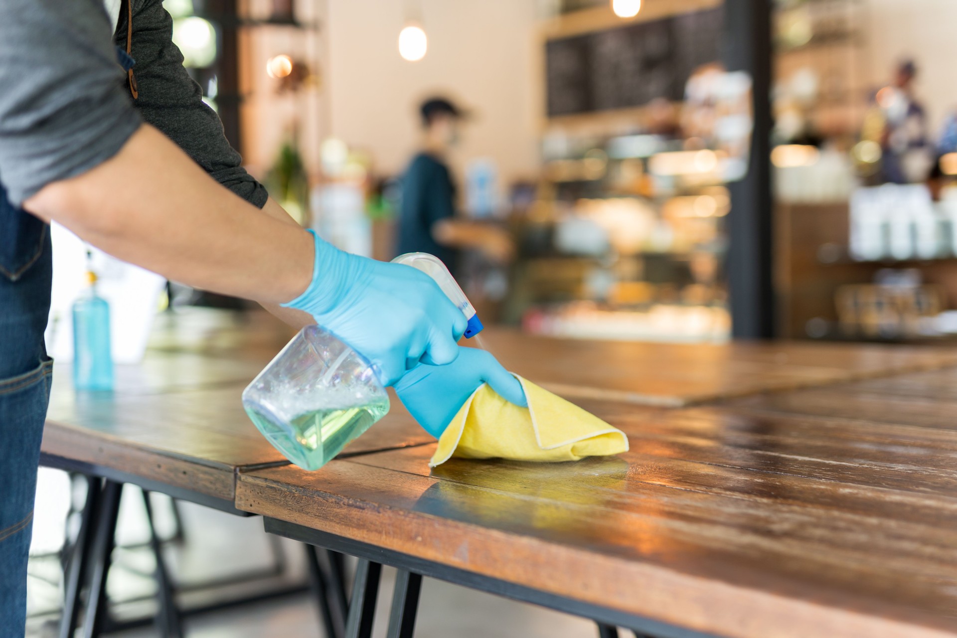 Waiter Cleaning Table With Disinfectant Spray In Restaurant Covid-19 Prevention